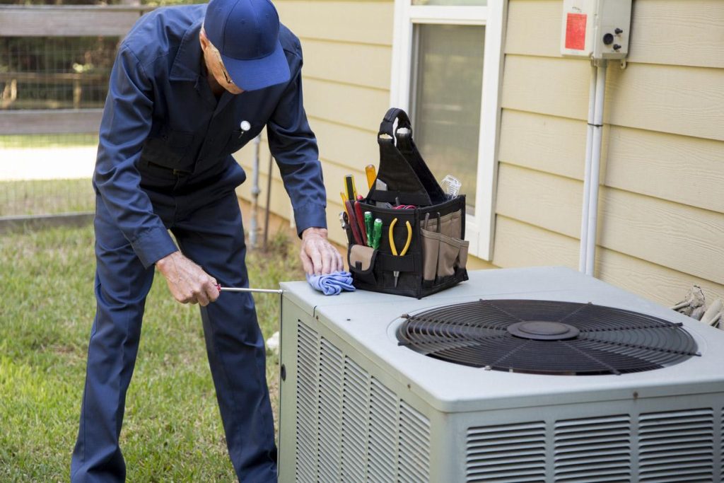 technician fixing a broken ac unit