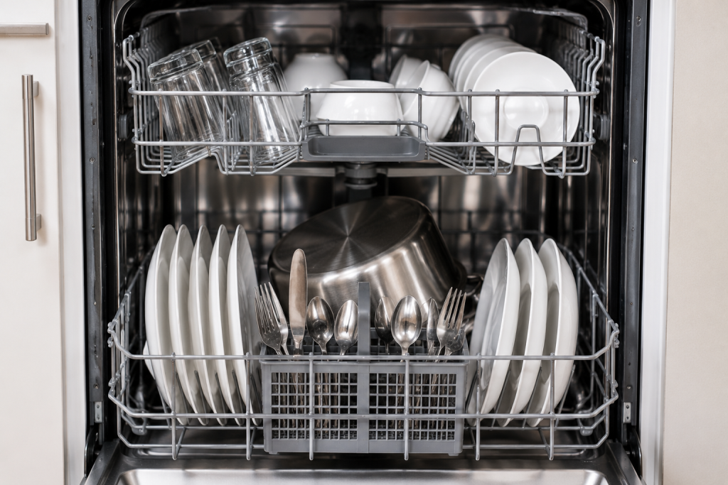 Properly loaded dishwasher with evenly spaced plates, glasses, and utensils arranged to allow full water spray coverage during a wash cycle